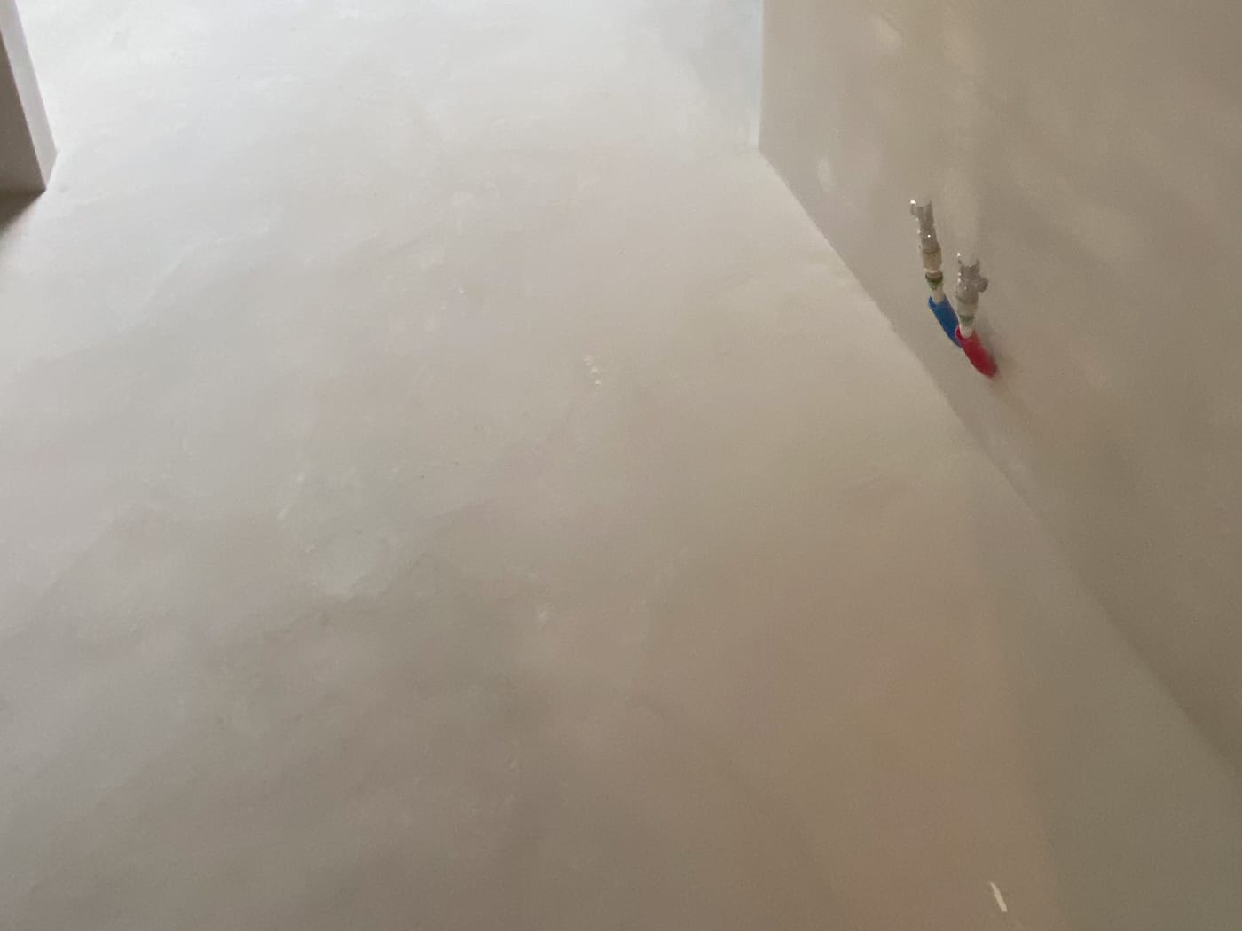Naadloze microcementvloer die doorloopt tot op de wand