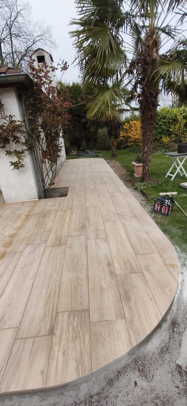 Afgewerkt terras met houtlook-tegels rond een palmboom
